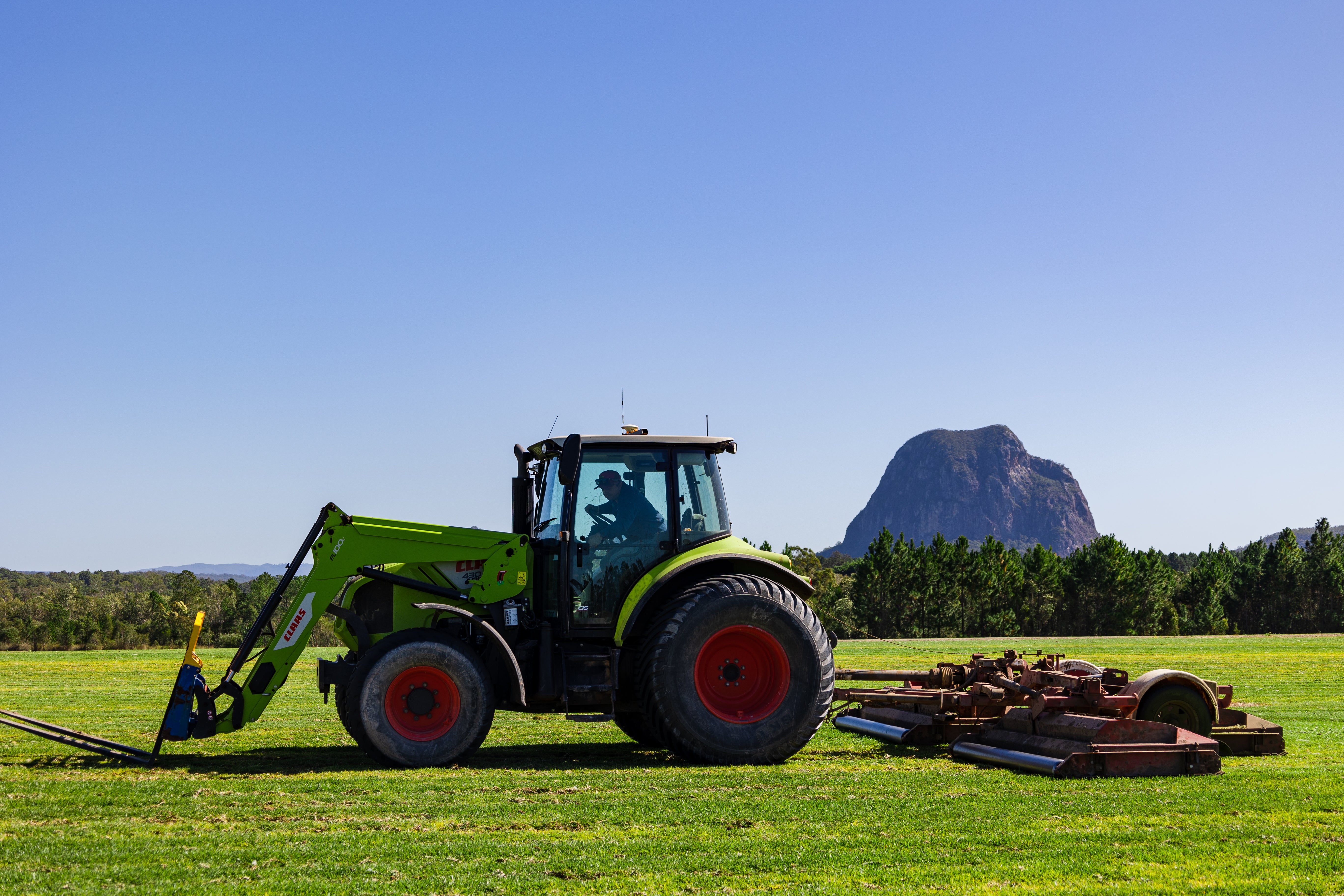 Tractor with Glasshouse Mountains in the background at Go Turf Farm on the Sunshine Coast